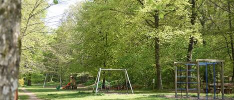 A park with a dirt path, a swing set, and a play structure.