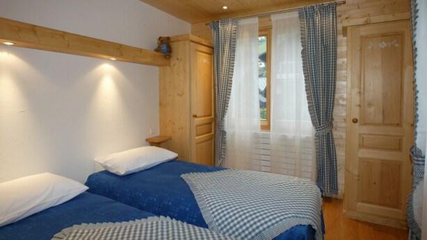 A room with two beds, wooden walls, and a window with checkered curtains. - 3 bedrooms, private parking, Wi-Fi, Les Gets (Les Gets)