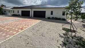 A two-story building with two garage doors, a paved driveway, and a gravel area.
