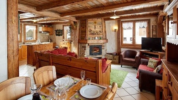 A rustic cabin interior with a dining area, a fireplace, a living room, and a kitchen.
