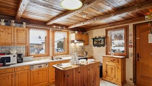 A kitchen with wooden cabinets, a central island, and a view of the outside through large windows.