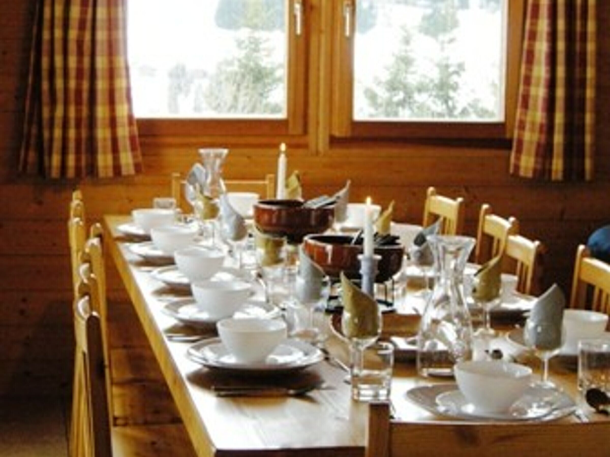 A dining table set for a meal with white plates, bowls, and glasses.