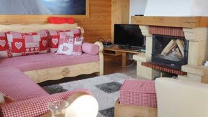 Una stanza accogliente con un divano in legno, una TV a schermo piatto e un camino.