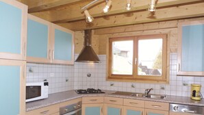 Una cucina con mobili azzurri, un forno a microonde bianco, un fornello, un lavello e una finestra con vista all'esterno.