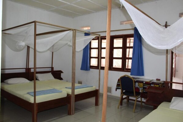 Cozy retreat with a four-poster bed, desk, and window.