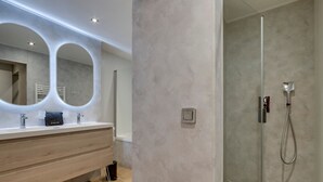 Une salle de bain moderne avec un meuble-lavabo en bois, deux grands miroirs et une douche à parois de verre.