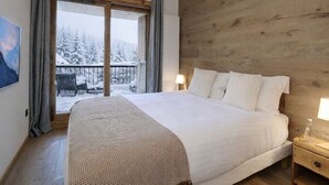 A bedroom with a large bed, wooden headboard, and a view of a snowy balcony. - New Ski-In/Ski-Out, 3 Bedrooms with WiFi and Parking (Courchevel 1650)