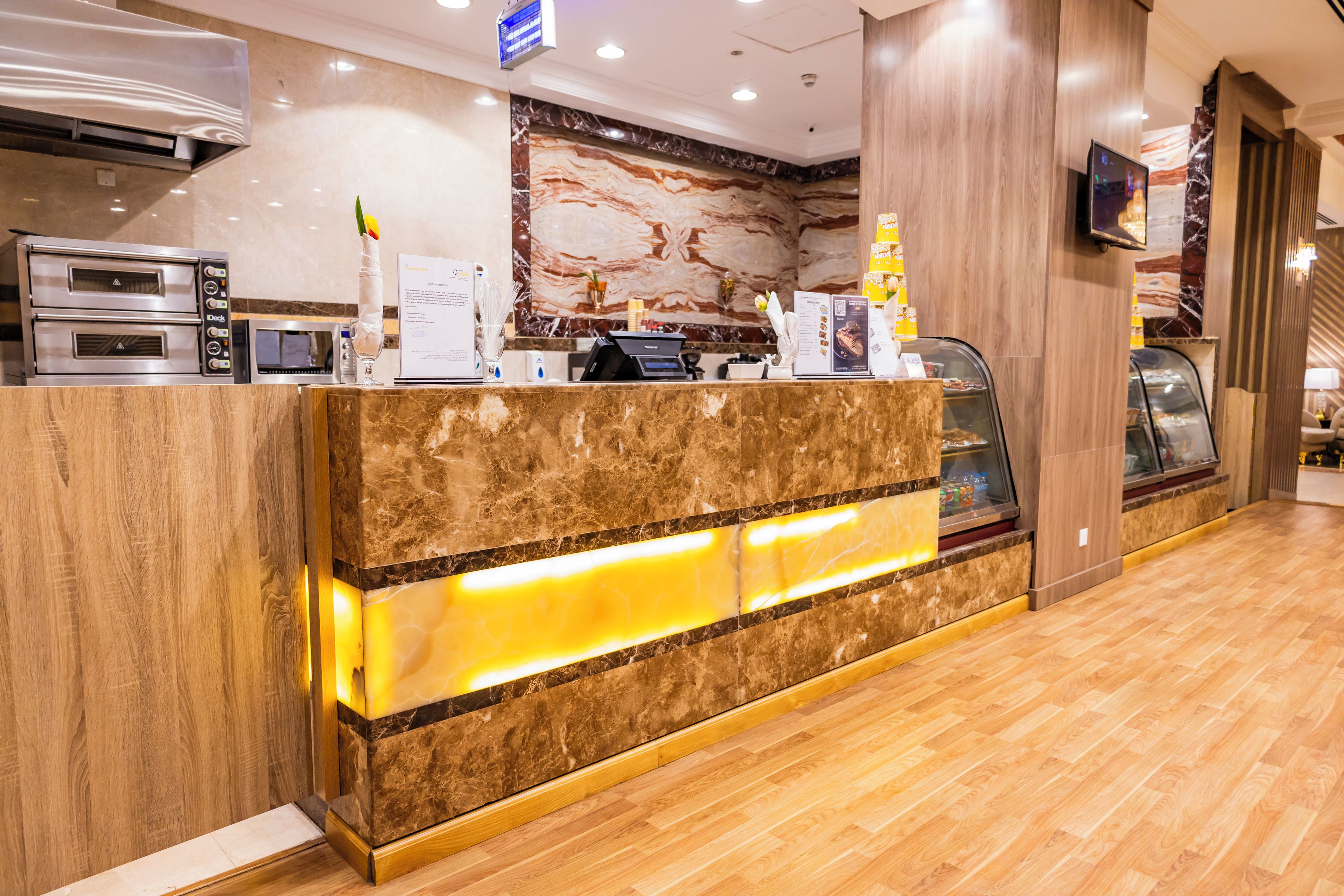 Un espace d’accueil d’hôtel avec un comptoir en marbre, une machine à café et un présentoir de menus.
