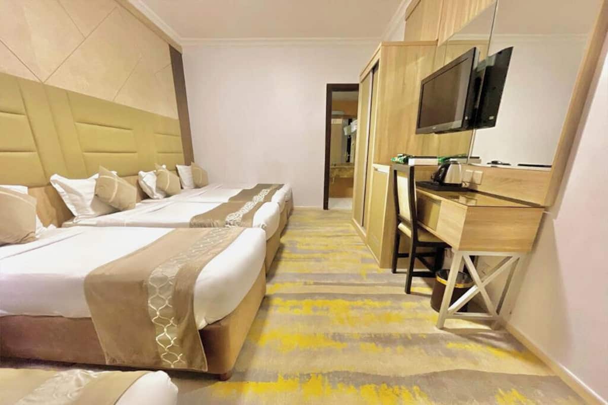 Une chambre d’hôtel avec deux lits, un bureau et une télévision.