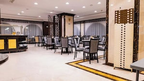A spacious dining area with multiple tables and chairs, a central decorative column, and a patterned wall.