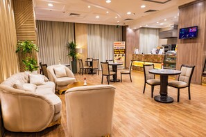 A hotel lobby with seating areas, a reception desk, and a television screen. - Al Mukhtara International Hotel (Madinah)