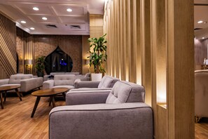 A modern lounge area with sofas, a coffee table, and a potted plant. - Al Mukhtara International Hotel (Madinah)
