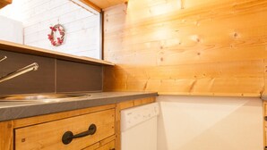 A wooden kitchen with a sink, a dishwasher, and a window with a wreath. - Cozy apartment for 4 in the heart of Avoriaz with Wifi (Avoriaz)