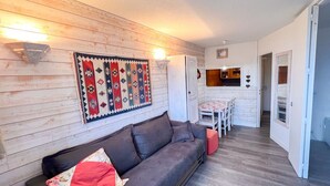 A cozy living room with a dark leather sofa, a patterned rug, and a dining area with a table and chairs. - Cozy apartment for 4 in the heart of Avoriaz with Wifi (Avoriaz)