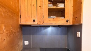 A kitchen with wooden cabinets, a stainless steel range hood, and a white dishwasher. - Cozy apartment for 4 in the heart of Avoriaz with Wifi (Avoriaz)