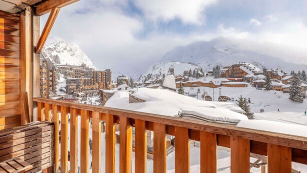 Ein Holzbalkon mit Blick auf eine schneebedeckte Bergstadt.