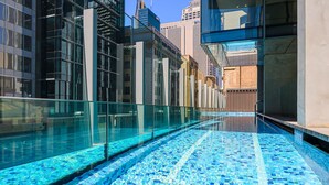 Ein modernes Hallenbad mit Glaswänden und Fliesenboden, umgeben von Hochhäusern.