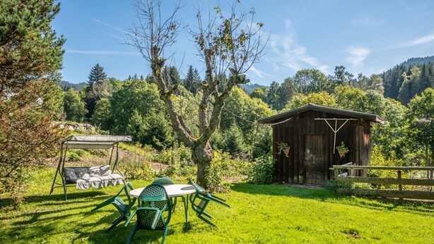 A rustic outdoor seating area with a swing set and a wooden structure, surrounded by lush greenery and trees. - Cozy apartment with Wi-Fi, parking and pets allowed (Les Gets)