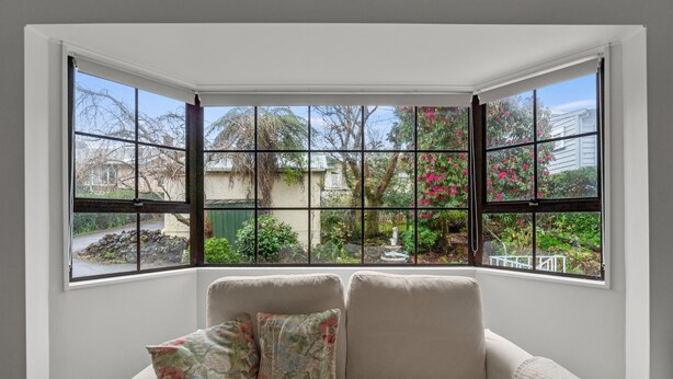 A corner room with a bay window overlooking a garden with a fountain. - Central Comforts - Mount Eden Holiday Home (Auckland)