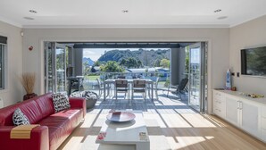 A modern living room with a red leather sofa, a coffee table, and a dining area with chairs and a table.