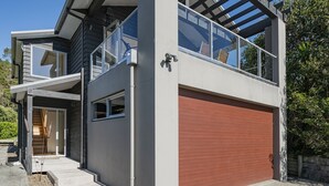 A modern two-story house with a garage, a balcony, and a staircase leading to the upper floor.
