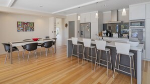 A modern kitchen with a central island, bar stools, and a dining area with a table and chairs.