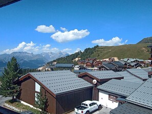 Une station de montagne avec des bâtiments en bois, un télésiège et une vue sur des montagnes enneigées.