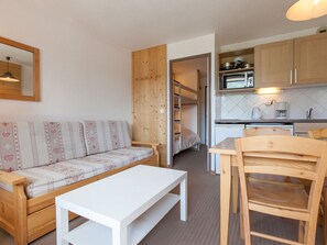 A compact living space with a sofa, a white table, a wooden chair, a bunk bed, and a kitchenette. - Charming studio for 4 in Avoriaz with balcony (Avoriaz)