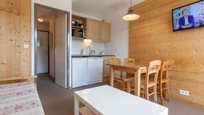A compact kitchen with modern appliances, a dining area with wooden chairs, and a television mounted on the wall. - Charming studio for 4 in Avoriaz with balcony (Avoriaz)