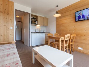 A compact kitchen with modern appliances, a dining area with wooden chairs, and a television mounted on the wall. - Charming studio for 4 in Avoriaz with balcony (Avoriaz)