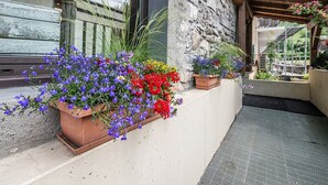 A balcony with potted flowers and a stone wall.