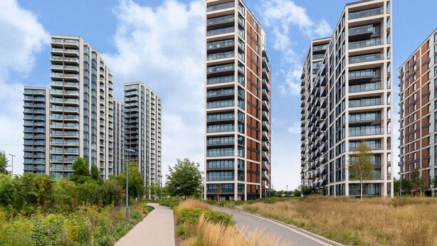 Un complexe résidentiel moderne composé d’immeubles de grande hauteur, d’une promenade dallée et d’espaces verts environnants.