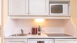 Una kitchenette compacta equipada con microondas, tostadora y lavavajillas.