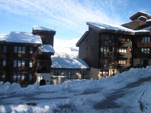 Um edifício coberto de neve com várias varandas e base de pedra, rodeado por neve.