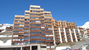 Un hôtel à plusieurs étages doté d’une façade en bois originale, de balcons et offrant une vue sur des montagnes enneigées.