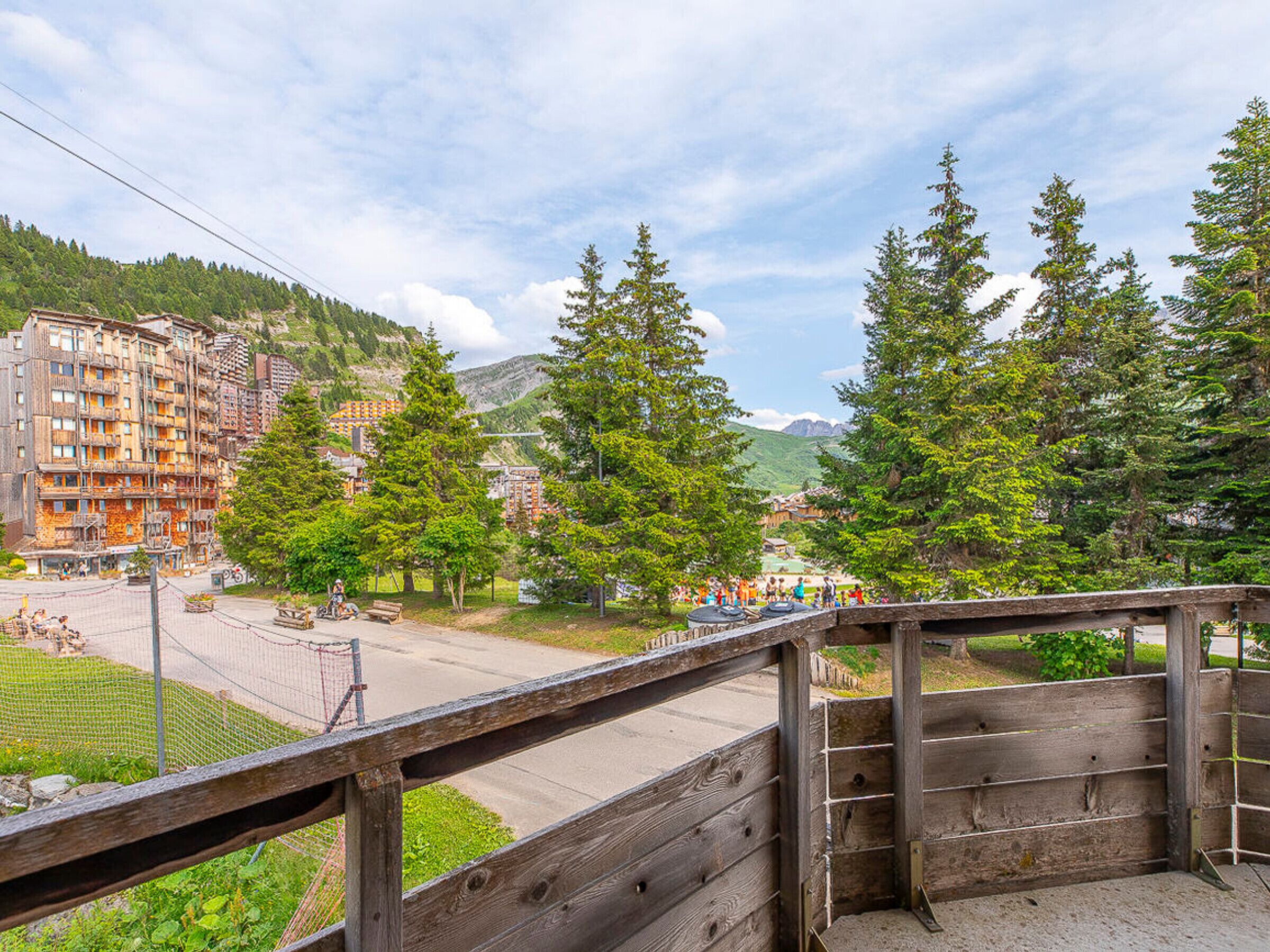 A wooden fence overlooking a town with buildings and trees.