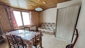 Una habitación acogedora con techo de madera, una mesa de comedor con sillas, un sofá y un radiador.