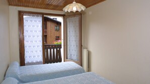 Un dormitorio con dos camas, techo de madera y vistas a un balcón con flores.