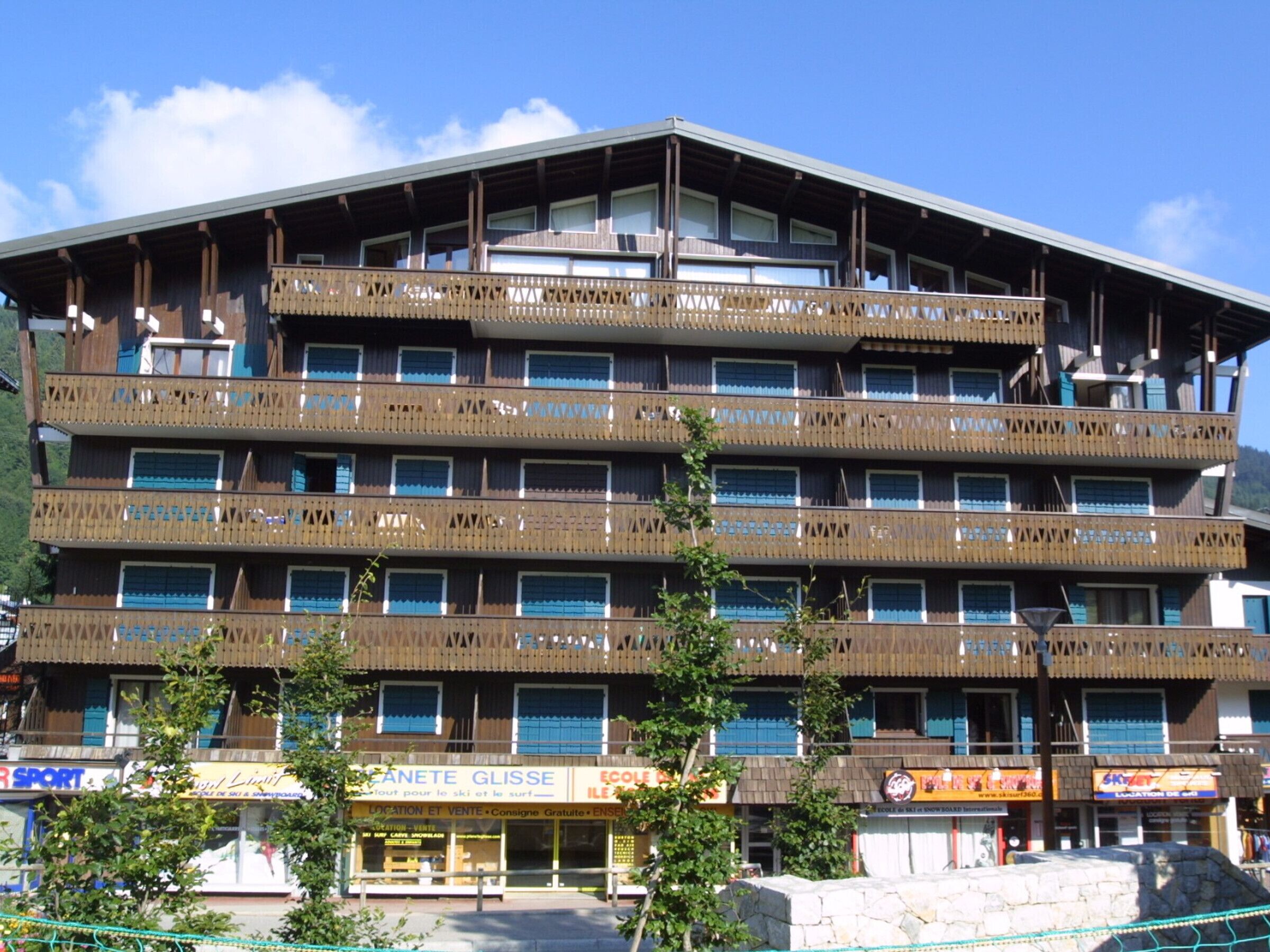 A multi-story hotel with balconies, a ski and surf shop, and a restaurant.