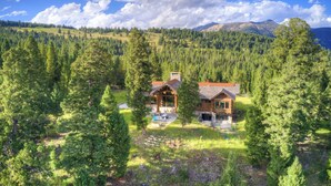 A cabin surrounded by dense forest, with a clear view of the mountains in the background. - Spanish Peaks Mountain Home - Big sky (Big Sky)
