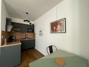 A compact kitchen with a microwave, sink, and a small dining area with a table and chair.