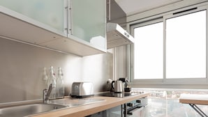 A modern kitchen with a large window, stainless steel appliances, and a wooden countertop.