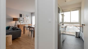 A modern apartment with a dining area, kitchen, and balcony.