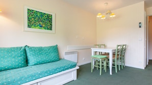 A small, cozy room with a teal sofa, a white table, and green chairs.