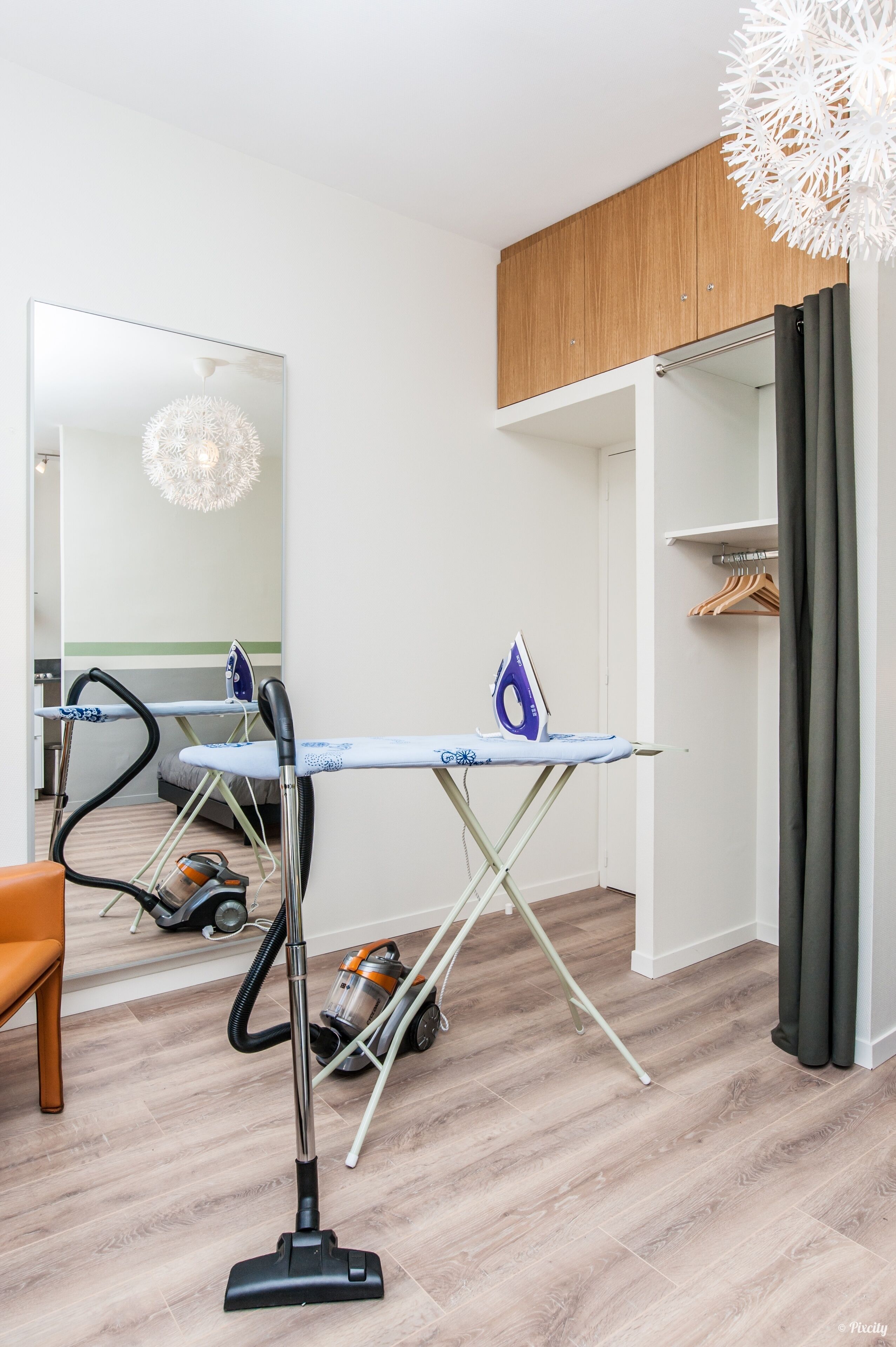 Una camera moderna con soffitto in legno, un asse da stiro, un aspirapolvere e una sedia.