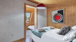 A bedroom with a wooden ceiling, a skylight, a bed with white bedding, and a framed artwork on the wall. - Spacious duplex for 9, central Val Thorens (Val Thorens)