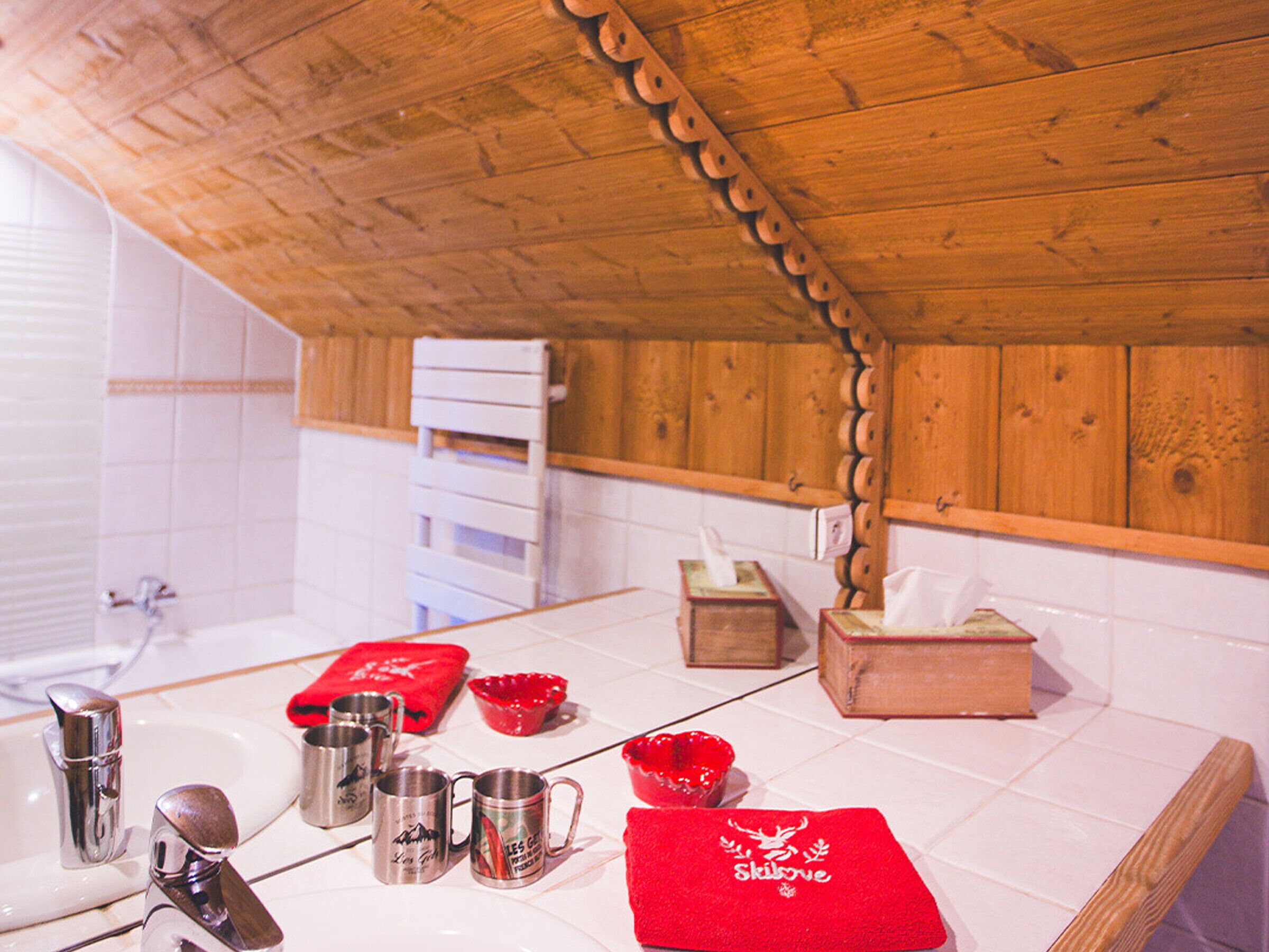 Une cuisine avec un plafond en bois, des carreaux blancs, un évier et des mugs en acier inoxydable.