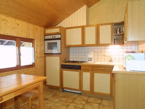 A compact kitchen with wooden cabinets, a stove, an oven, and a dishwasher. - Spacious Apartment for 8 with WiFi, Balcony, and Near Ski Lifts – Pet Friendly (Les Gets)