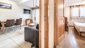 Une chambre moderne avec une porte en bois, un lit, un bureau et un téléviseur.