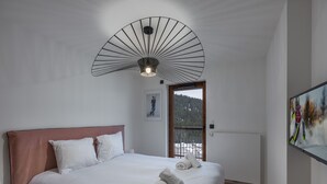 Ein Schlafzimmer mit einem großen Bett, einem Deckenventilator, einer Tür, die auf einen Balkon führt, und einem Gemälde an der Wand.